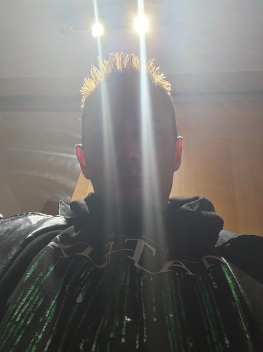 Mann mit hellen Lichtern im Hintergrund und glitzerndem Oberteil.